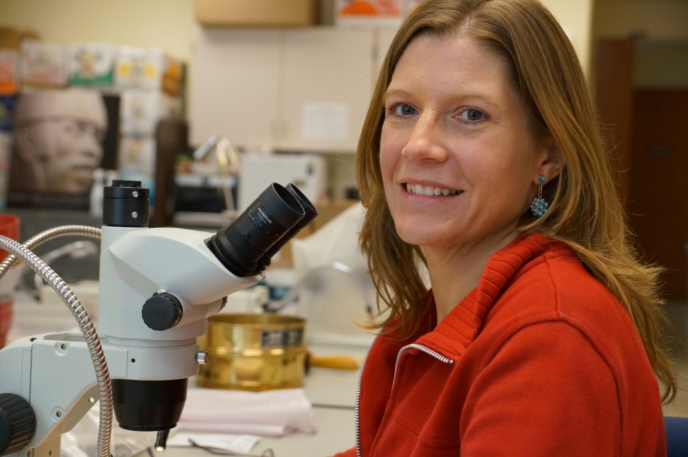 Amber Vanderwarker in a lab next to a microscope